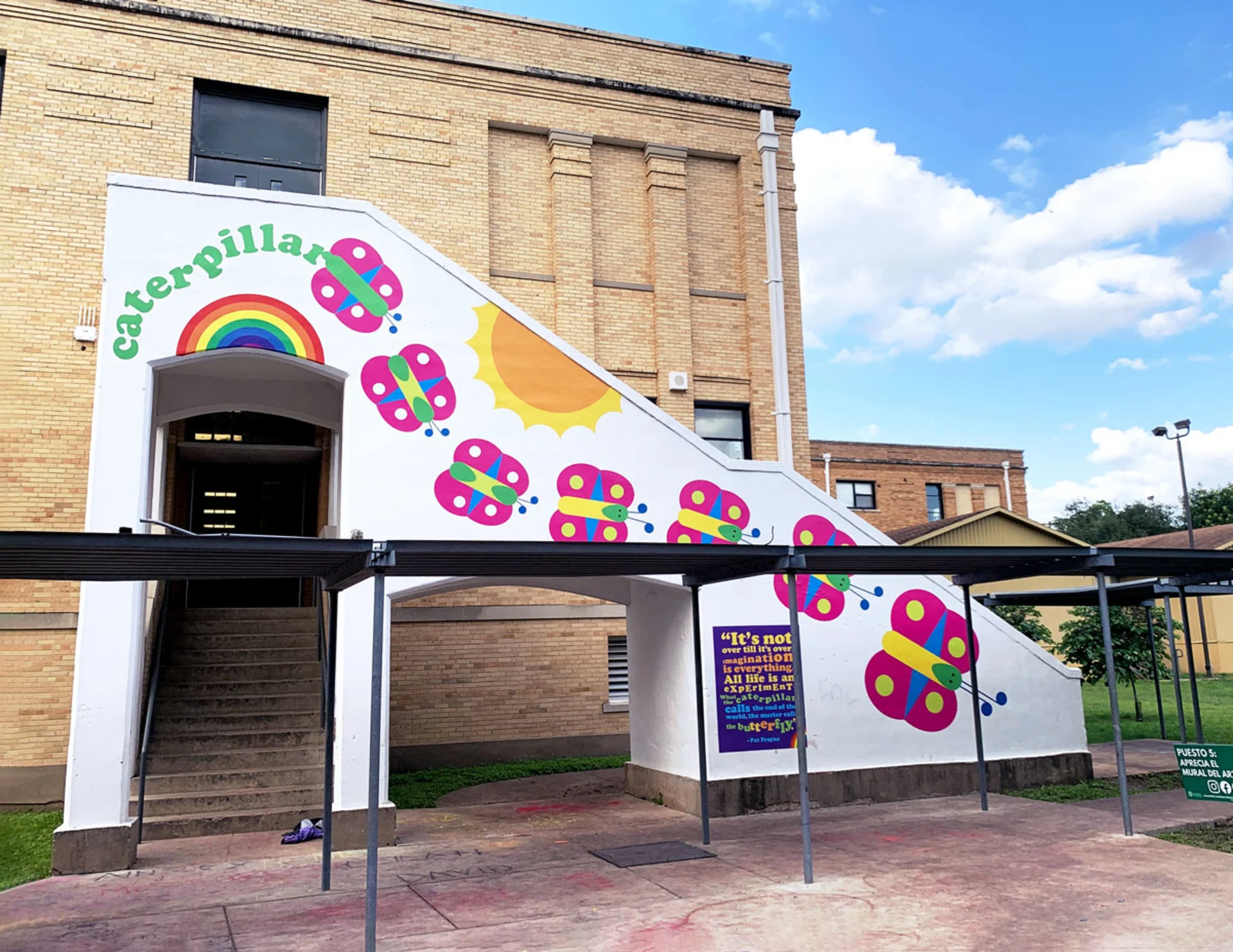 A white staircase outside Sam Houston Elementary is covered in a childlike illustration of a rainbow, a sun, butterflies lined up in a row, and the word, 'Caterpillar'.