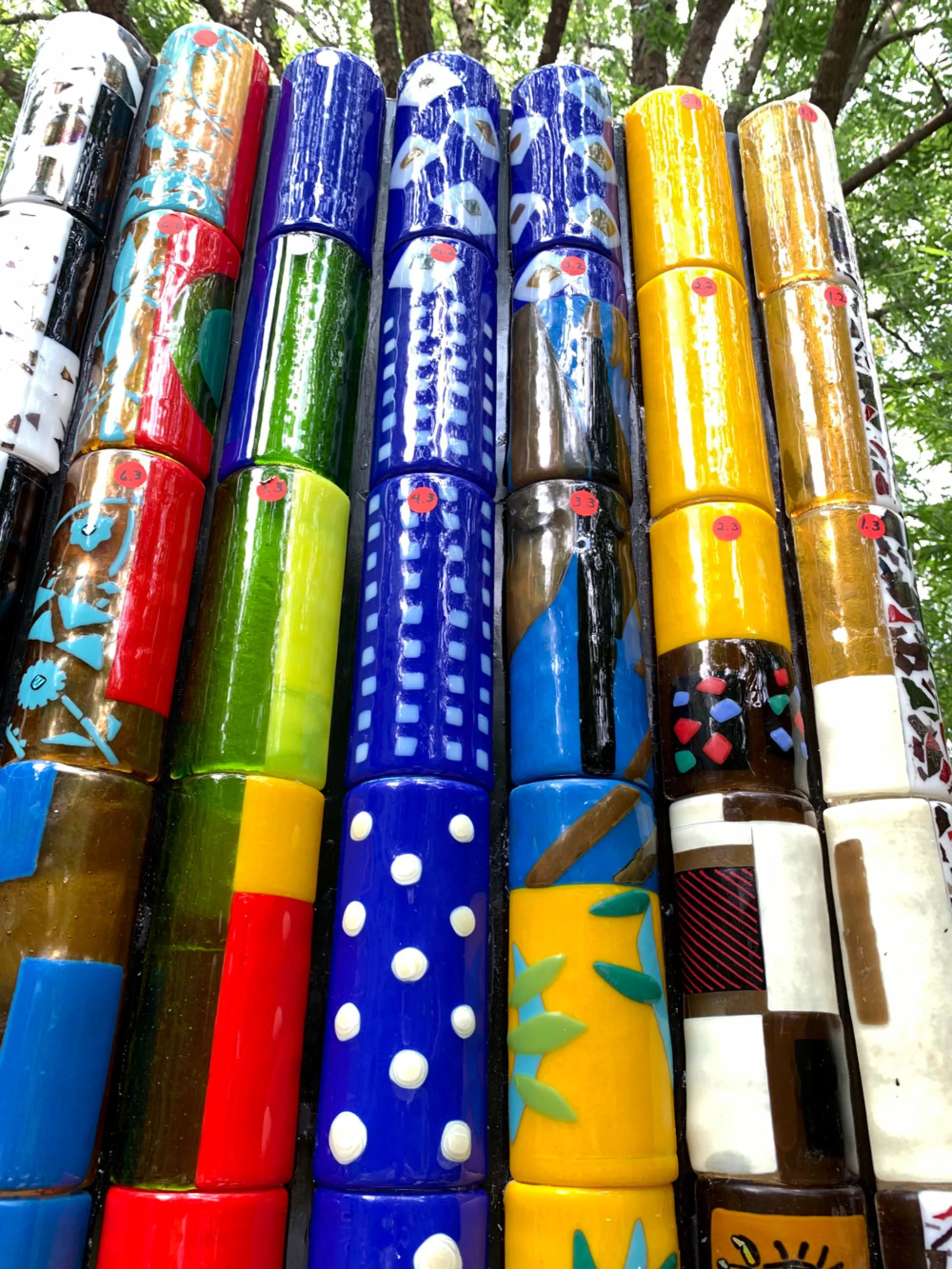Bright red, blue, yellow and green patterned glass cylinders glint in the sun.