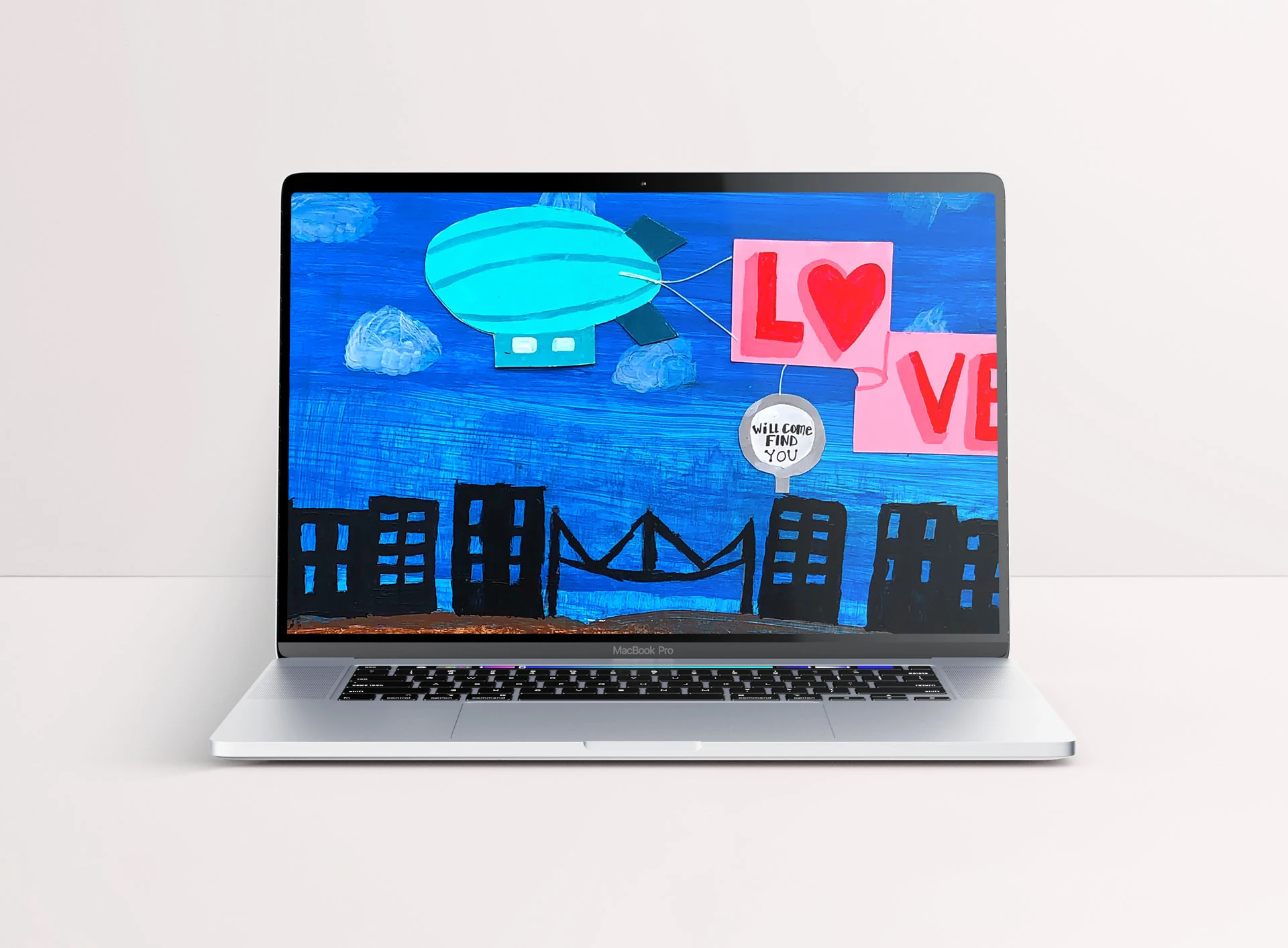 Laptop wallpaper mockup featuring artwork of a blimp with a large pink banner with the text 'Love... will come find you' flying over buildings.
