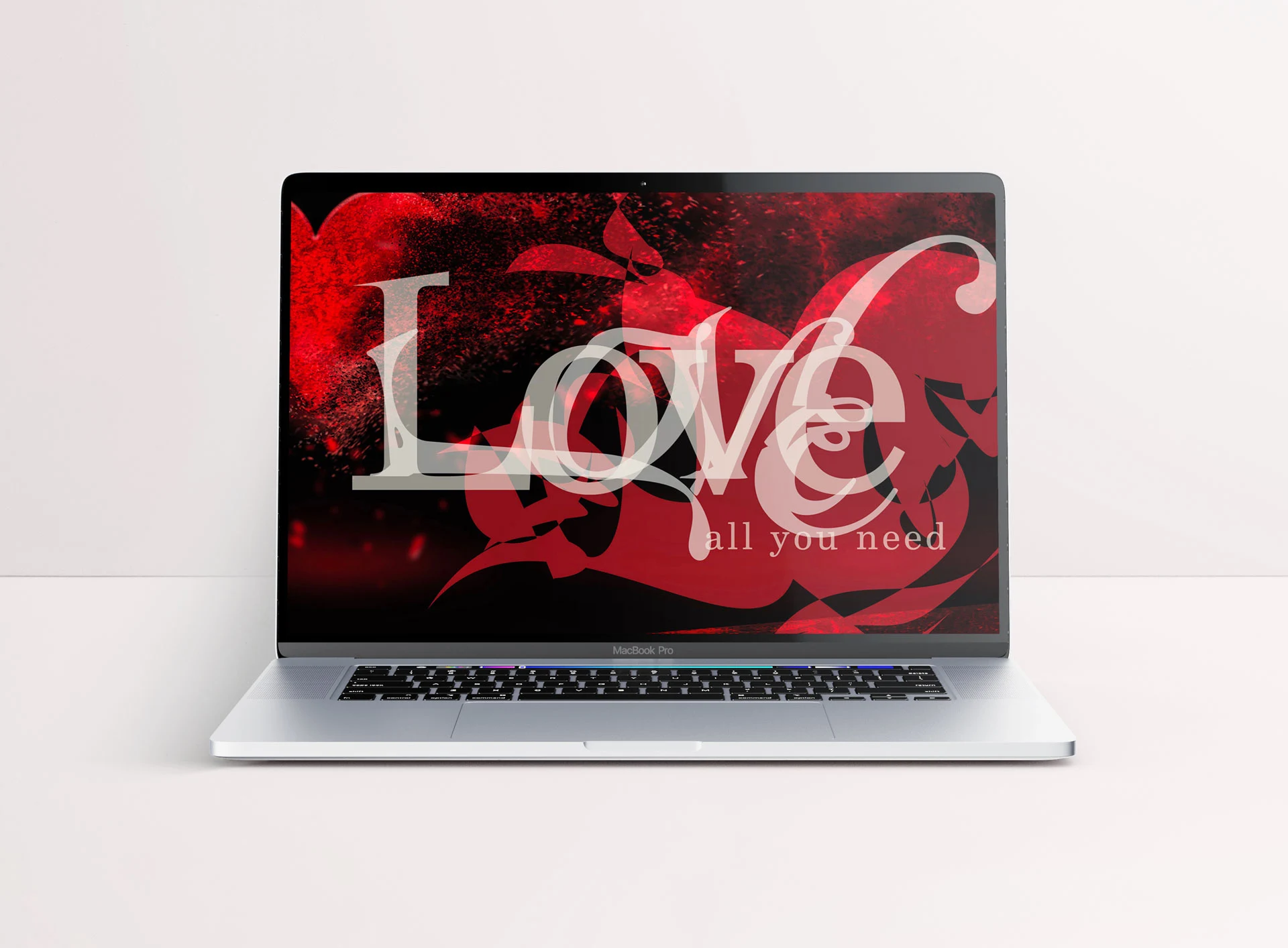 Laptop wallpaper mockup featuring a graphic illustration of the word 'Love' in bold, large text against an abstract red background followed by the text 'all you need'.