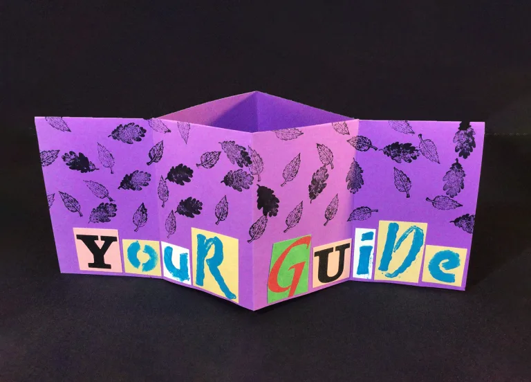A purple zine with stamped images of leaves, halfway folded to reveal the words "Your Guide" in cutout letters.