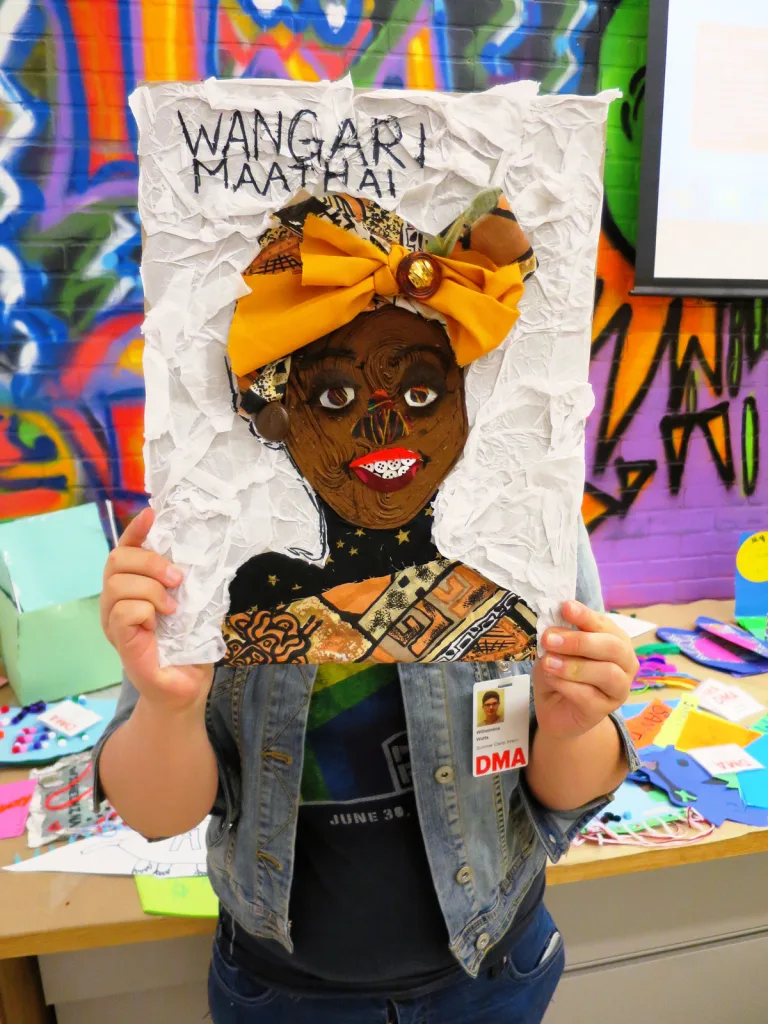 A young girl holds up a collage portrait of Kenyan political activist Wangarĩ Maathai.