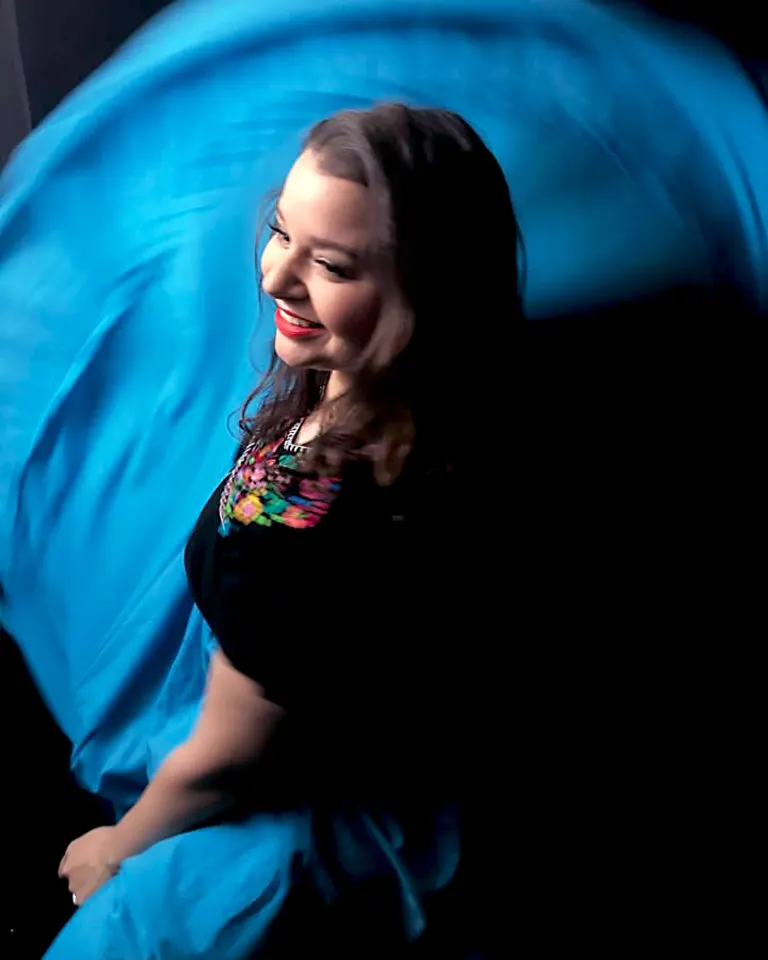 Candid birds-eye view portrait of Huggins, who is looking off camera, smiling and twirling her dress, which is in motion.