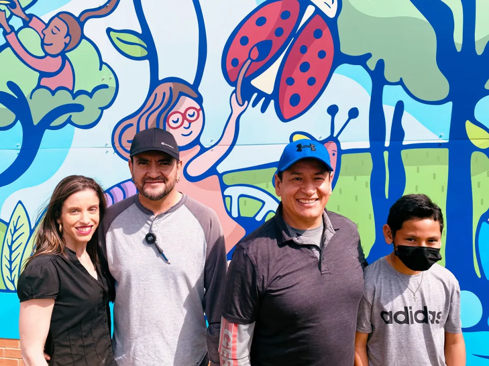 Thomas Printworks crew members smile and pose with family in front of the Burnet mural.