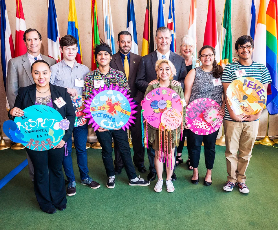 Blessen, Rawlings and other city officials stand in a row next to six student interns, who are each holding up the colorful respect-themed artwork they made.