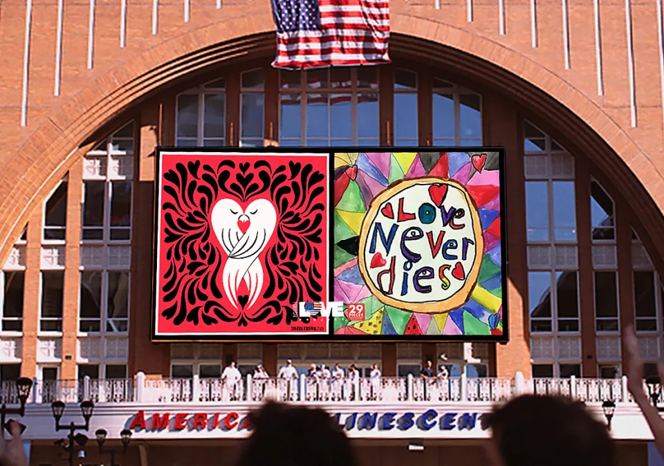 View of a large digital screen featuring artwork of two birds embracing and the text "Love Never Dies" outside the plaza of the American Airlines Center in Dallas, Texas.
