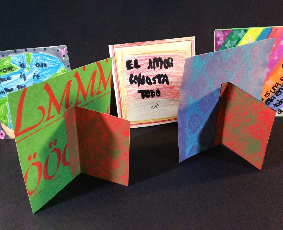 A collection of square artwork sitting at a 90 degree angle, with some facing backwards to show an easel back made of paper.